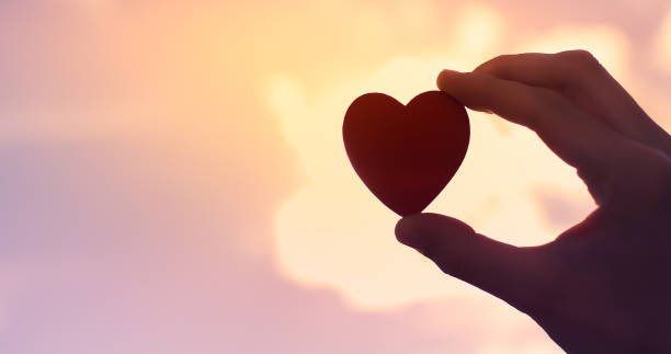 istock Hand holding up red heart against a sunset. 1217875574