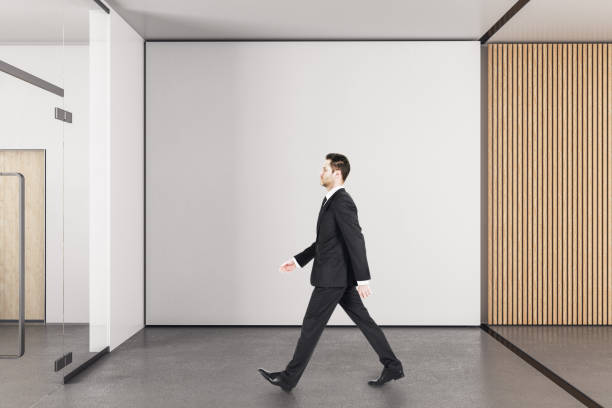 istock Businessman walking in office with copy space on wall. 1217877340