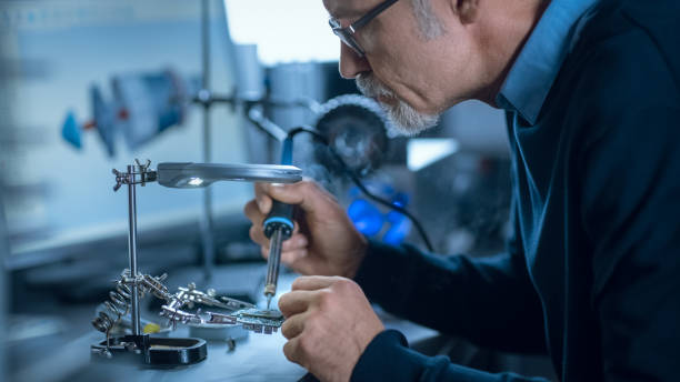 istock Portrait of Focused Middle Aged Engineer in Glasses Working with High Precision Laser Equipment, Using Lenses and Testing Optics for Accuracy Required Electronics 1217883623
