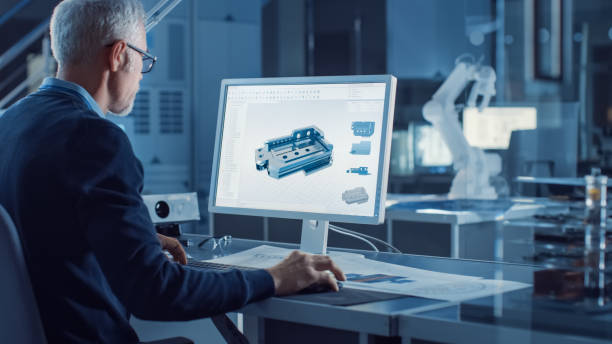 istock Professional Heavy Industry Engineer Works on Computer Uses CAD Software to Design 3D Industrial Machinery Component. In the Background Robot Arm Concept. Over the Shoulder Shot 1217883644