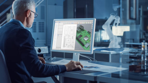 istock Engineer Works on Computer Uses CAD Software to Design 3D Industrial Machinery Component. In the Background Robot Arm Concept Standing in Heavy Industry Engineering Facility. Over the Shoulder Shot 1217883680