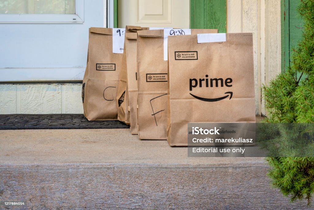 Home delivery of groceries from Whole Food Market Fort Collins, CO, USA - March 31, 2020: Brown bags with groceries and fresh produce delivered to house from Whole Food Market and order through Amazon Prime. Online shopping during coronavirus pandemic concept. Amazon Prime Stock Photo