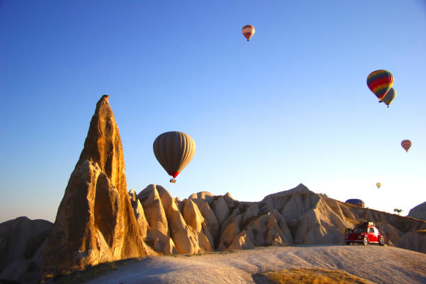 Hot air balloons in Cappadocia "Cappadocia, Turkey - July 5th, 2019: An awesome volkswagen beetle stands among the balloons in the early morning. tufa photos stock pictures, royalty-free photos & images