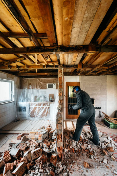 Mature worker damaging wall in house