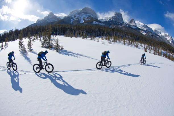 Fat Biking at the Canmore Nordic Centre A digital composite photo of a young man going for a winter fat bike ride at the Canmore Nordic Centre in Alberta, Canada. Fat bikes are mountain bikes with oversized wheels and tires for riding on the snow. He wears a cycling helmet, carries a backpack and wears warm winter cycling clothes. canadian rockies photos stock pictures, royalty-free photos & images