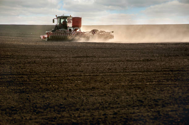istock tractor work plow the field with durst . Agricultural works for processing, tillage. Farmers preparing the land and fertilizing. Farmland, tractor with seeder, sowing and fertilizer 1217885278