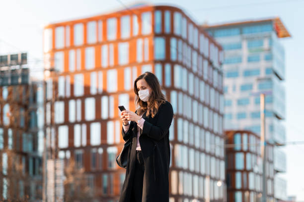 istock Commuter with medical face mask using her smart phone 1217886006