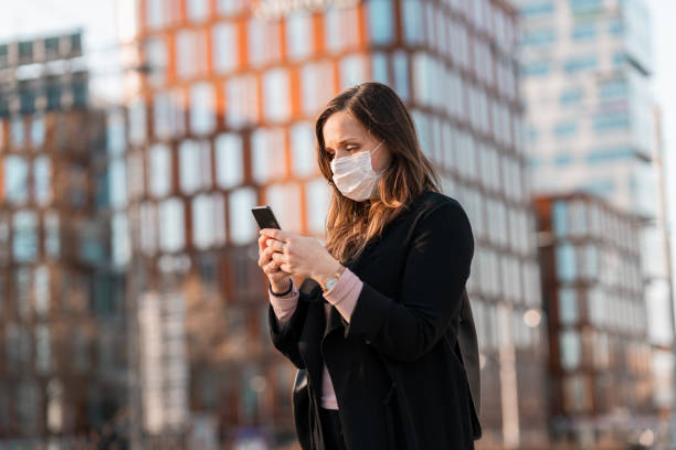 istock Commuter with medical face mask using her smart phone 1217886009