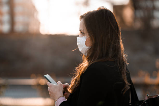 istock Commuter with medical face mask using her smart phone 1217886018