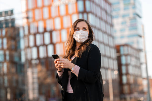 istock Commuter with medical face mask using her smart phone 1217886021
