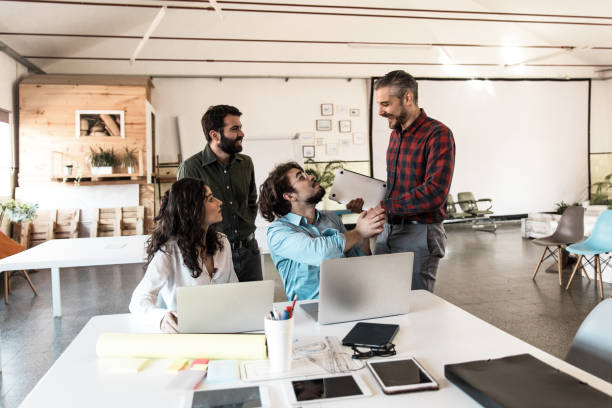 istock Positive startup group with laptops chatting in meeting room 1217888356