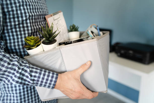 primo parziale di ignoti caucasici in possesso di una scatola con oggetti personali che lasciano l'ufficio dopo essere stati licenziati dal lavoro a causa della recessione economica che ha perso la chiusura dell'azienda - close up businessman corporate business side view foto e immagini stock