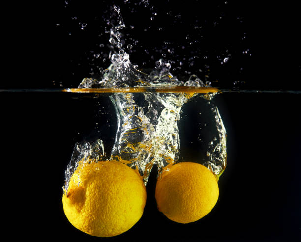 istock Falling lemons in water, spray for design, freezing in motion. Water splash and vegetables isolated on a black backgroud 1217889686