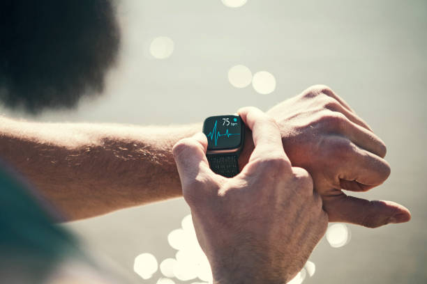 Man running outdoors running checking smart watch taking a break Man running outdoors in the city smart watch stock pictures, royalty-free photos & images