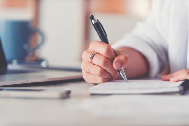 istock Woman writing on a pad working at home sitting at the dining room table. 1217890628