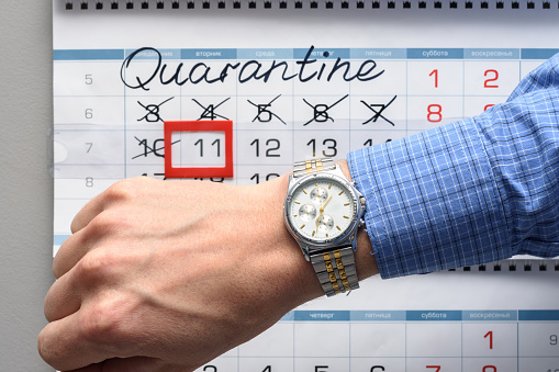 The hand on which the watch is worn, in the background a calendar with the inscription Quarantine