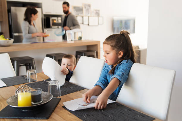 弟と妹が昼食時にテーブルをセットするのを手伝っています。 - テーブルセッティングする ストックフォトと画像