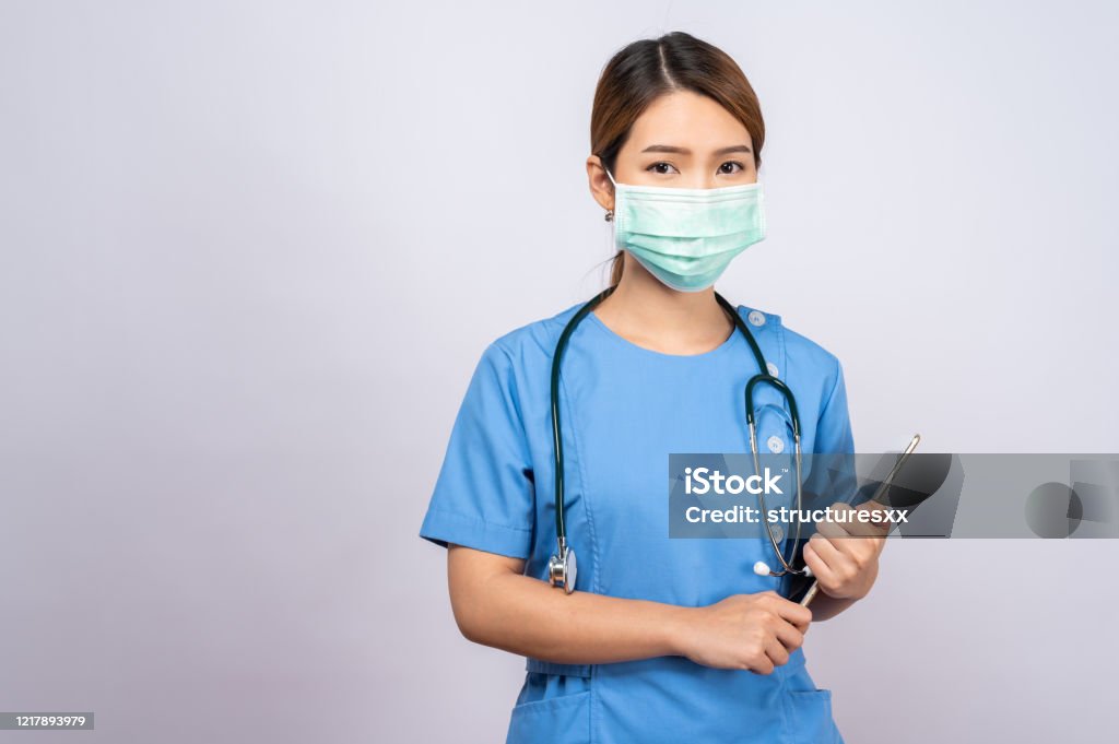Verticale de jeune infirmière asiatique utilisant le masque chirurgical - Photo de Suivi des malades libre de droits
