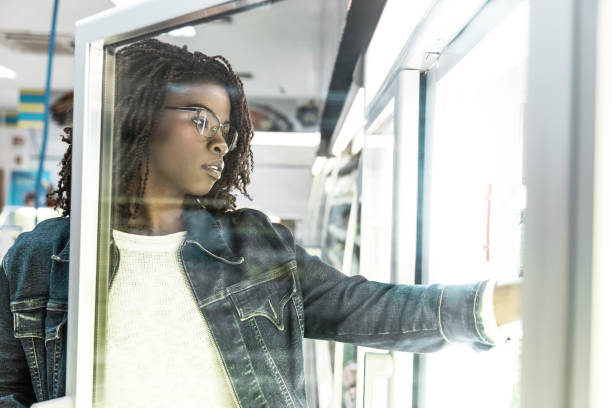 istock Young female customer taking food from fridge shelf 1217895021