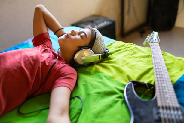 Latinx pre-teen boy listening to music calmly in his bedroom stock photo