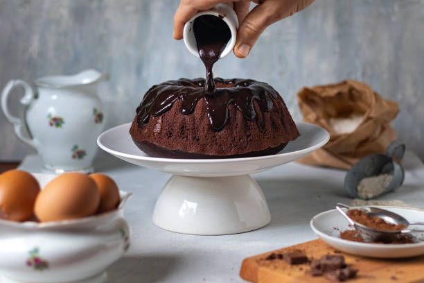 schokoladen-eis auf den kuchen gießen - chocolate cake stock-fotos und bilder