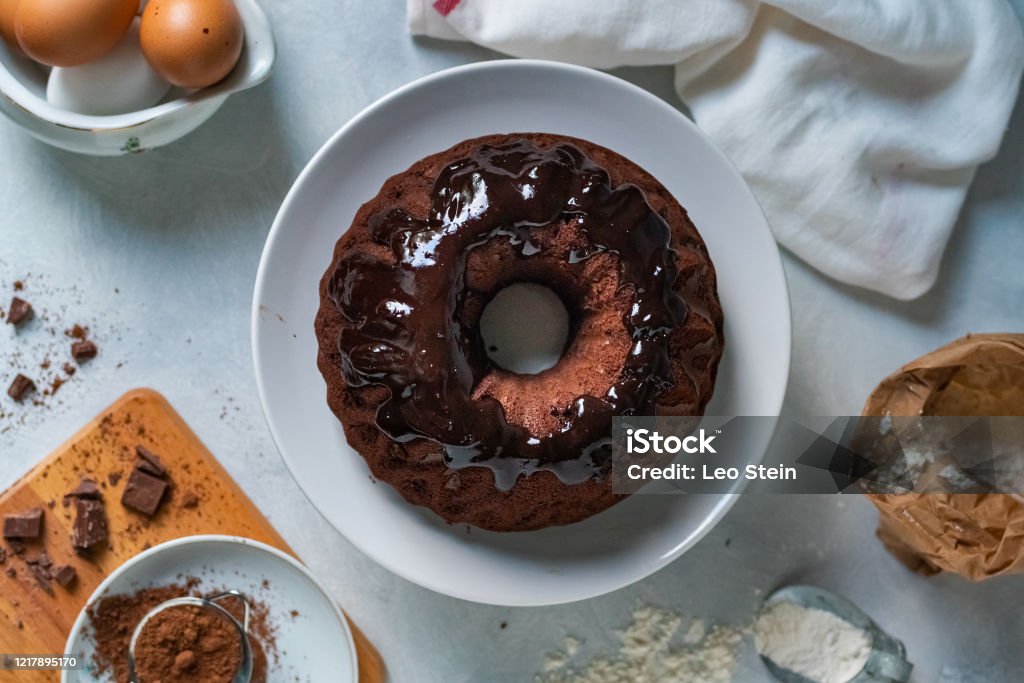 A beautiful chocolate cake A table arranged with the ingredients to make a chocolate cake and the finished cake in the center High Angle View Stock Photo