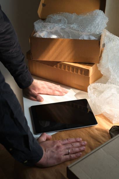 istock A man is packing cardboard boxes. Delivery service for online orders. Holding tablet in hand. The guy working in office, the cargo business. Warehouse with products, preparation for express shipping 1217897248