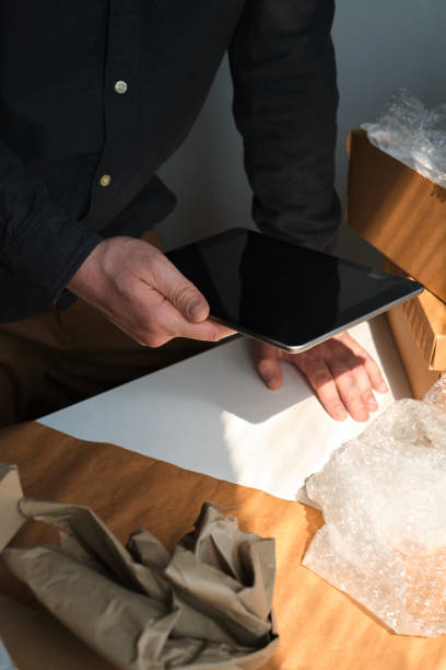 istock A man is packing cardboard boxes. Delivery service for online orders. Holding tablet in hand. The guy working in office, the cargo business. Warehouse with products, preparation for express shipping 1217897306