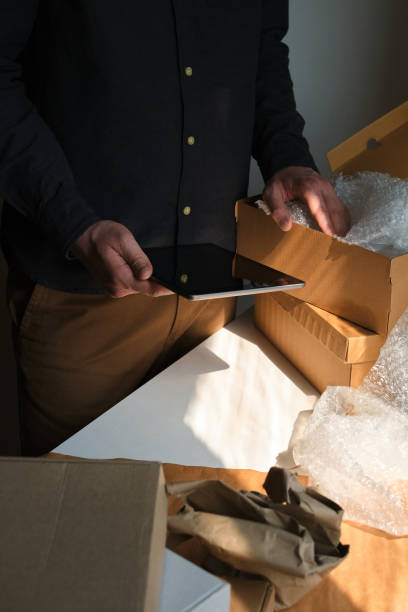 istock A man is packing cardboard boxes. Delivery service for online orders. Holding tablet in hand. The guy working in office, the cargo business. Warehouse with products, preparation for express shipping 1217897311