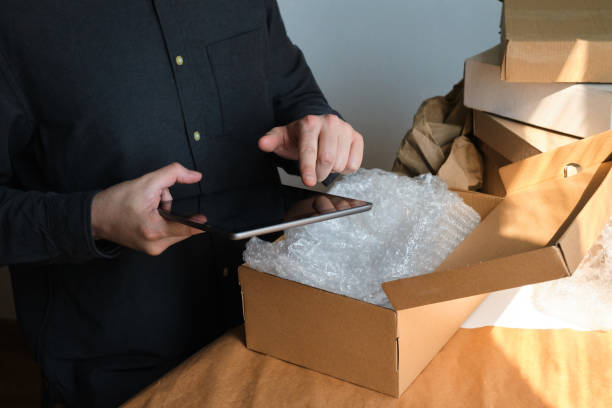 istock A man is packing cardboard boxes. Delivery service for online orders. Holding tablet in hand. The guy working in office, the cargo business. Warehouse with products, preparation for express shipping 1217897329