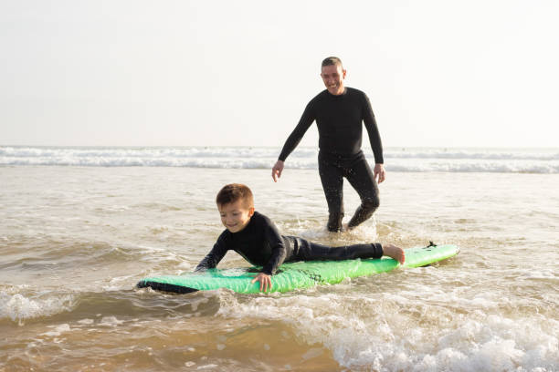 istock Cute little boy learning surf-riding with father 1217897559