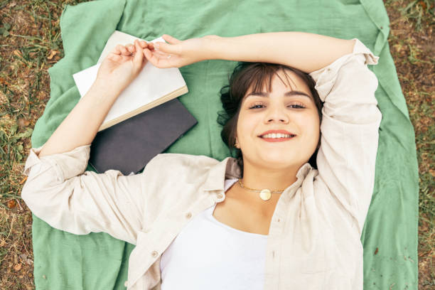 istock Cheerful female student lying on green meadow 1217897609