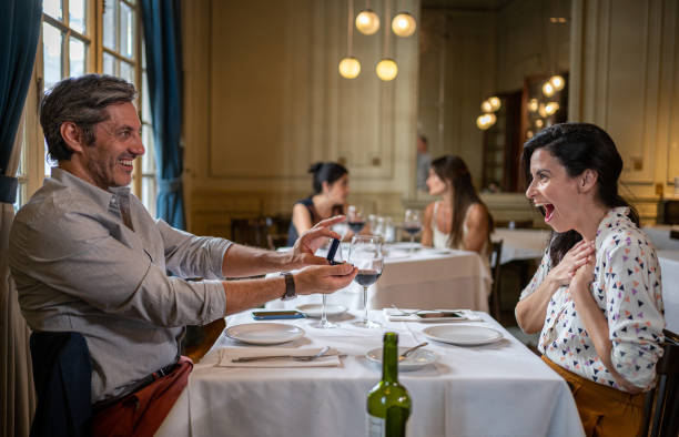 istock Handsome boyfriend proposing to a beautiful girlfriend at a restaurant 1217898457