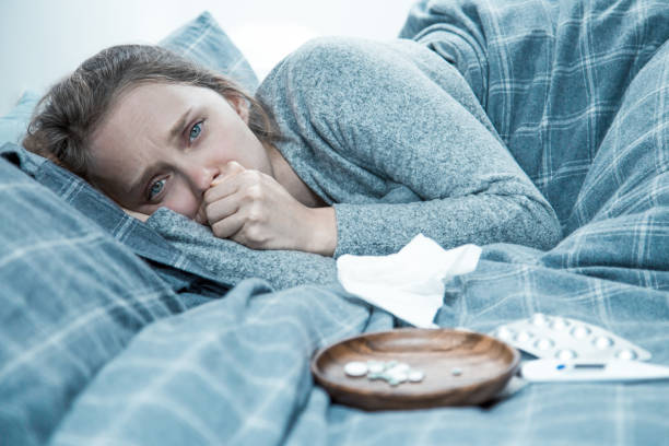 istock Sick young woman lying in bed, coughing 1217900057