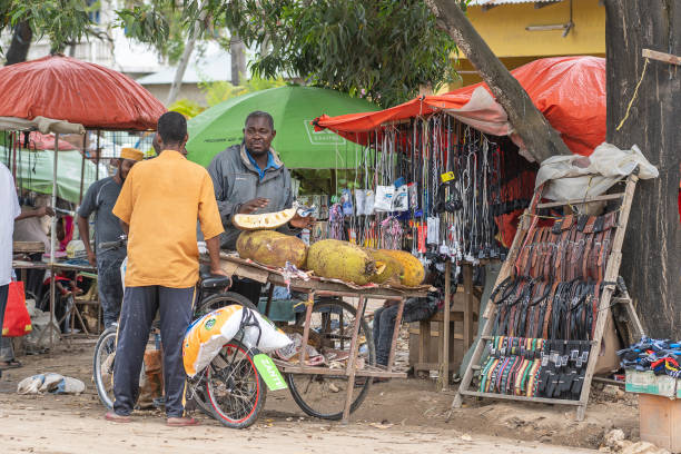 l'uomo africano vende frutta tropicale in un mercato locale di cibo di strada sull'isola di zanzibar, tanzania, africa orientale - africa agriculture zanzibar industry foto e immagini stock