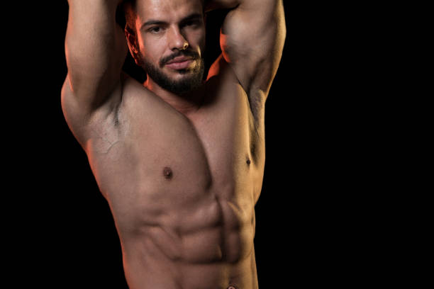 istock Muscular Model Flexing Muscles On Black Background 1217909174