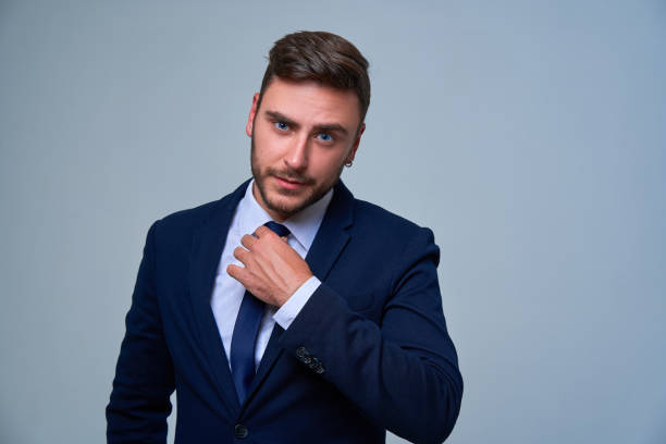 fermez vers le haut le jeune homme d’affaires de verticale. fond gris de studio de costume d’affaires de type caucasien. - suit necktie close up gray photos et images de collection