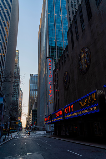 Manhattan, New York, USA - April 7, 2020: The night view on Radio City Music Hall along W50th Street deserted because of the COVID-19 outbreak.