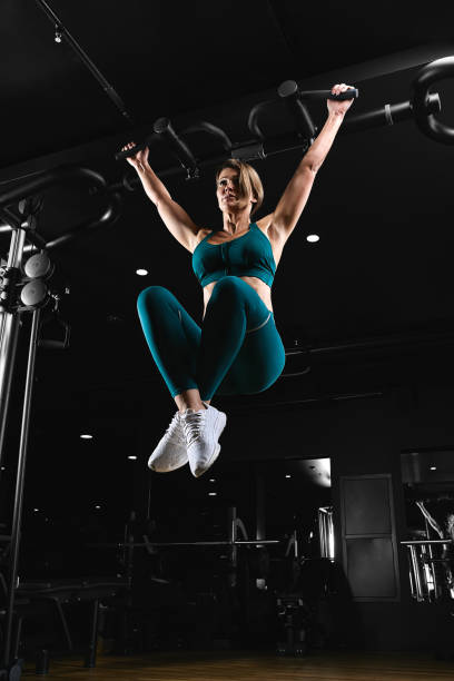 istock Woman working out in gym - pull ups. Image cross processed, contrasty, dark grainy image 1217912953