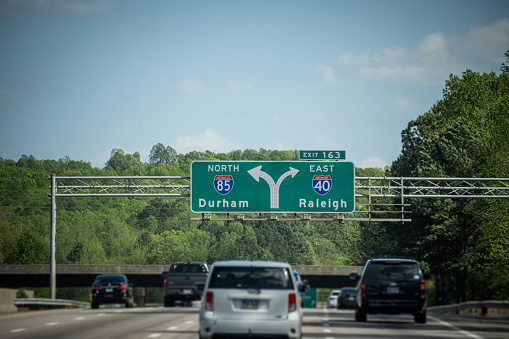 A large overhead highway sign leads drivers to Raleigh and/or Durham, NC, USA.