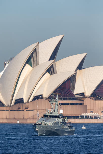 hmas broome (acpb 90) barco patrulha classe armidale da marinha real australiana em sydney harbor com a sydney opera house ao fundo. - sydney australia sydney opera house australia sydney harbor - fotografias e filmes do acervo