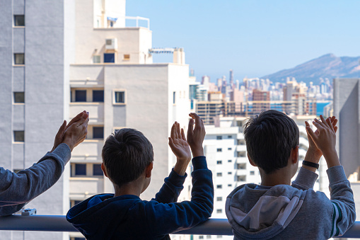 Family applauding medical staff from their balcony. People in Spain clapping on balconies and windows in support of health workers during the Coronavirus pandemic