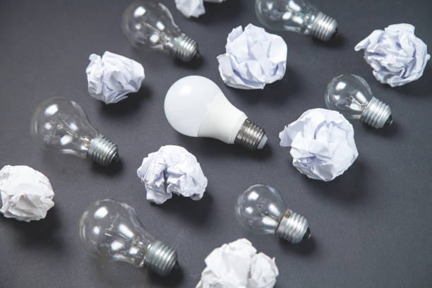 istock Light bulb and crumpled papers in the black background. Idea 1217941520