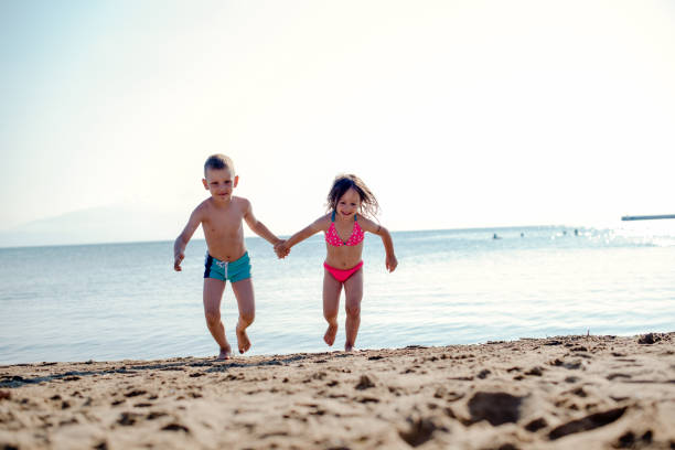 istock Brother and sister running from the water 1217942207