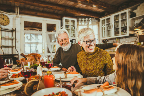 Happy grandparents talking to their granddaughter during Thanksgiving lunch. Happy senior grandparents communicating with their small granddaughter during a Thanksgiving meal at dining table. Focus is on woman. turkey meat photos stock pictures, royalty-free photos & images