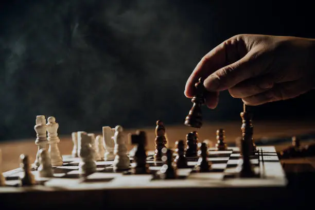 Photo of Close up of hands of men playing chess.