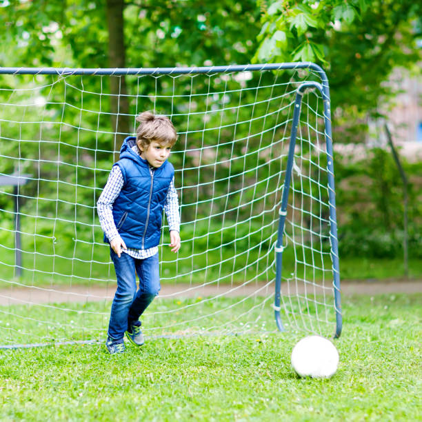 istock Active school kid boy playing soccer and kicking ball. 1217948510