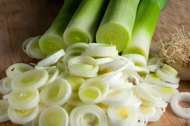 close-up of leek cut into slices with fresh stems on a wooden cutting board