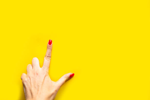 istock Woman's hand shows the point gesture over bright yellow background. Minimal concept. Copy space for the text 1217950345