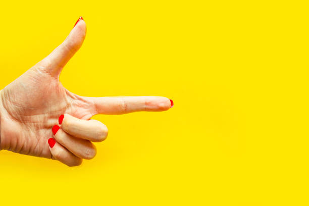 istock Woman's hand shows the point gesture over bright yellow background. Minimal concept. Copy space for the text 1217950352